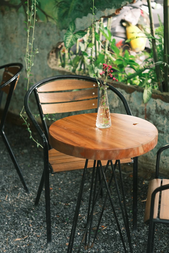 An inviting outdoor cafe scene with a wooden table and a vase of flowers, ideal for relaxation.