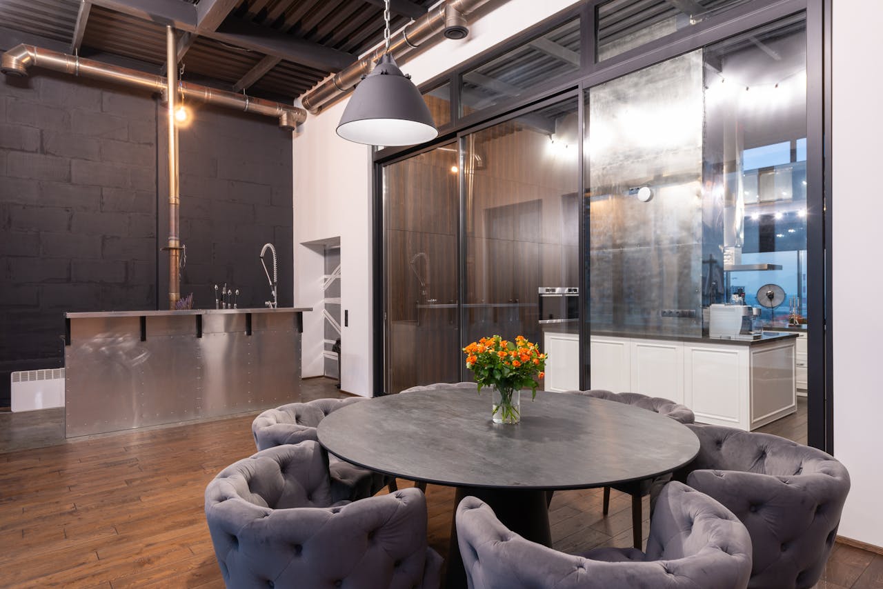 Interior of spacious dining room with round table with bouquet of flowers and comfortable chairs against glass wall in modern apartment